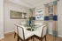 Chic dining room with elegant glass table, stylish white chairs, and ocean-themed decor creating a sophisticated ambiance.