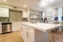 Chic modern kitchen with sleek white cabinets, stainless steel appliances, and elegant dining area featuring ocean-themed artwork.