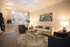 Inviting living room with elegant decor, featuring a cozy beige sofa, stylish blue armchairs, and a chic glass coffee table illuminated by warm lighting.