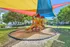Vibrant outdoor playground with colorful shade sails, perfect for children's fun and relaxation amidst lush greenery.
