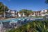 Resort-style swimming pool with lounge chairs, palm trees, and surrounding apartment homes on a clear, sunny day.