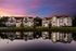 Apartment homes along a waterfront at sunset with soft evening lighting and reflections on the water.