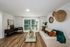 Bright living room with modern furnishings, wood-style flooring, decorative wall accents, and large windows with natural light.