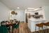 Open-concept apartment home featuring a living area, dining space, and kitchen with a breakfast bar, modern finishes, and wood-style flooring.