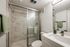 Modern bathroom with a walk-in shower, marble-style wall surrounds, glass enclosure, and contemporary vanity.
