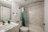 Guest bathroom with a soaking tub, marble-style wall surrounds, glass enclosure, and contemporary vanity.