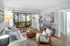 Chic and modern living room with elegant decor, featuring a stylish grey sofa, vibrant yellow cushions, and large window with striped curtains overlooking greenery.