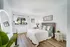Cozy bedroom featuring a plush bed with pastel accents, elegant bedside table with soft lighting, and stylish wall art for a serene atmosphere.
