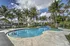 Resort-style swimming pool with lounge chairs, palm trees, and surrounding apartment homes on a clear, sunny day.