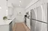 Bright and modern kitchen with sleek stainless steel appliances, elegant white cabinets, and a spacious quartz countertop, perfect for stylish cooking and entertaining.