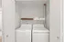 Bright laundry room with modern washer and dryer, featuring ample shelving and elegant wood flooring.