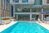 Outdoor pool with lounge chairs, umbrellas, and surrounding cityscape.