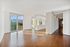 Spacious empty apartment with wood floors, large windows, and an open kitchen layout.