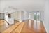 Spacious apartment with white walls, wood flooring, large windows, and a modern kitchen island.