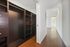 Walk-in closet with dark wood shelving and drawers, adjacent to a bright hallway with hardwood floors.