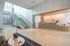 Contemporary apartment lobby with a glass staircase, concierge desk, and modern seating area with orchid centerpiece.