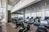 Modern gym with treadmills, exercise bikes, free weights, and floor-to-ceiling windows.