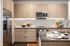 Contemporary kitchen with light wood cabinets, stainless steel appliances, white tile backsplash, and a center island with place settings.