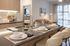 Modern kitchen island with place settings and a sleek faucet, leading into a cozy living room with a leather sofa and large window.