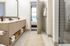 Contemporary bathroom with a double vanity, woven storage baskets, and a view into the bedroom.