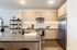Sleek kitchen with light wood cabinetry, stainless steel appliances, and a large island with a built-in sink and faucet.