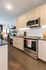 Close-up view of a modern kitchen with light wood cabinets, stainless steel oven and microwave, and decorative accents on the counter.