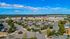 Aerial exterior view of a suburban shopping center with a large parking lot, various retail stores including Harris Teeter, surrounding townhomes, and a backdrop of rolling hills and blue sky.