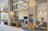 Modern and stylish lounge area with contemporary furniture, pendant lighting, a large wooden coffee table, and a textured accent wall. Natural light fills the space through floor-to-ceiling windows.