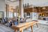 Modern apartment clubhouse with lounge seating, wood accents, pendant lighting, and a shuffleboard table in the center.
