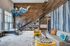 Stylish apartment lobby with modern decor, a staircase with built-in shelving, colorful geometric art, cozy seating with vibrant pillows, and marble flooring.