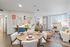 Bright and stylish apartment living and dining area with cozy seating, a round wooden table set for four, colorful wall art, and large windows letting in natural light.
