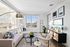 Bright, modern living room with a large sectional sofa, cozy accent chair, decorative rug, statement lighting, wall art, and expansive windows letting in natural light.