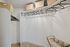 Spacious walk-in closet with beige storage bins, black hangers on wooden rods, and a fabric laundry cart on carpeted flooring.