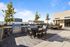 Outdoor rooftop kitchen and dining area with stainless steel grills, dining table, and fire pit lounge seating under a clear blue sky.