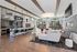 Modern resident lounge with open seating, a large communal table, patterned accent walls, and natural light from full-length windows.