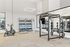 Modern gym space with weight racks, resistance training equipment, and a cardio machine against a mirrored wall.