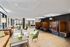 Stylish resident lounge with leather seating, work booths, and modern decor featuring natural wood floors and ample lighting.
