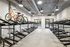 Indoor bike storage room with double-decker racks, featuring a few parked bicycles on the top tier and many empty spaces, under bright ceiling lights and industrial-style decor.