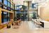 Modern apartment lobby with high ceilings, floor-to-ceiling windows, contemporary lighting fixtures, cozy seating areas, and a welcoming front desk.