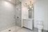 Modern bathroom with a glass-enclosed walk-in shower, white vanity with a large mirror, and a toilet, all in a sleek, minimalist design.