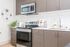Contemporary kitchen with stainless steel appliances, including a microwave and oven, flat-panel wood cabinets, and a white tile backsplash.