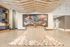 Open coworking space featuring a large mural, modern wood ceiling design, and flexible seating areas with neutral decor and ample lighting.