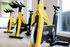 Close-up of bright yellow stationary bikes in a dedicated indoor cycling room with natural light streaming through nearby windows.