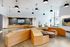 Spacious modern lobby featuring tiered wooden seating, a mounted TV, minimalist pendant lights, and large windows allowing natural light.