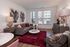 Living room with large windows, modern furniture, bold artwork, and a red area rug creating a warm, inviting space.