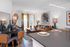 Open-concept apartment with a stylish living room, dining area, and kitchen island; featuring colorful decor, large windows, and a leather sofa.