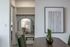 Close-up view of a dining table with green vases, modern wall art, and a decorative mirror reflecting a cozy interior.