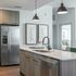 Contemporary kitchen with stainless steel appliances, pendant lighting, and a sleek island with an integrated sink.