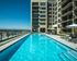 Rooftop swimming pool surrounded by lounge chairs, overlooking downtown Denver with mountain views in the distance.