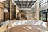 Spacious apartment lobby with high ceilings, glass staircase, wood flooring, and natural light.